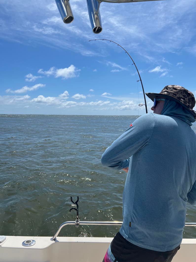 A man is fishing on a boat in the ocean.