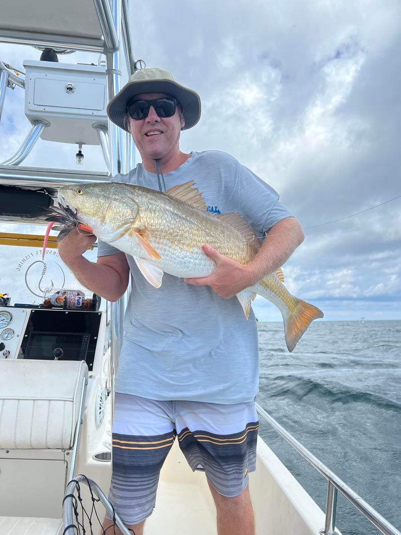 A man is holding a large fish on a boat.
