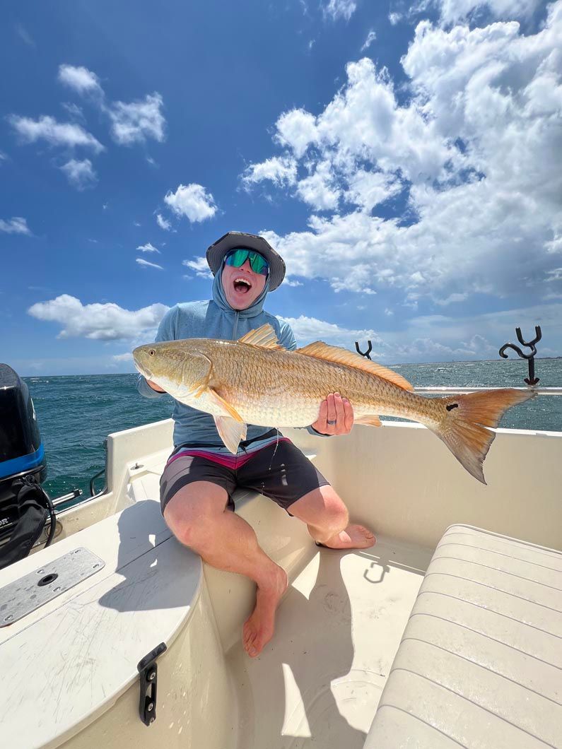 A man is sitting on a boat holding a large fish.