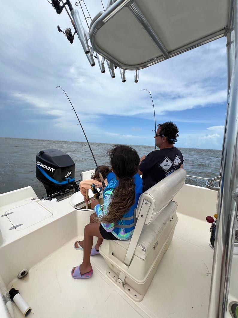 A man and two children are fishing on a boat.