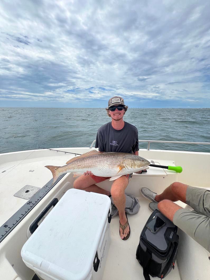 A man is sitting on a boat holding a large fish.