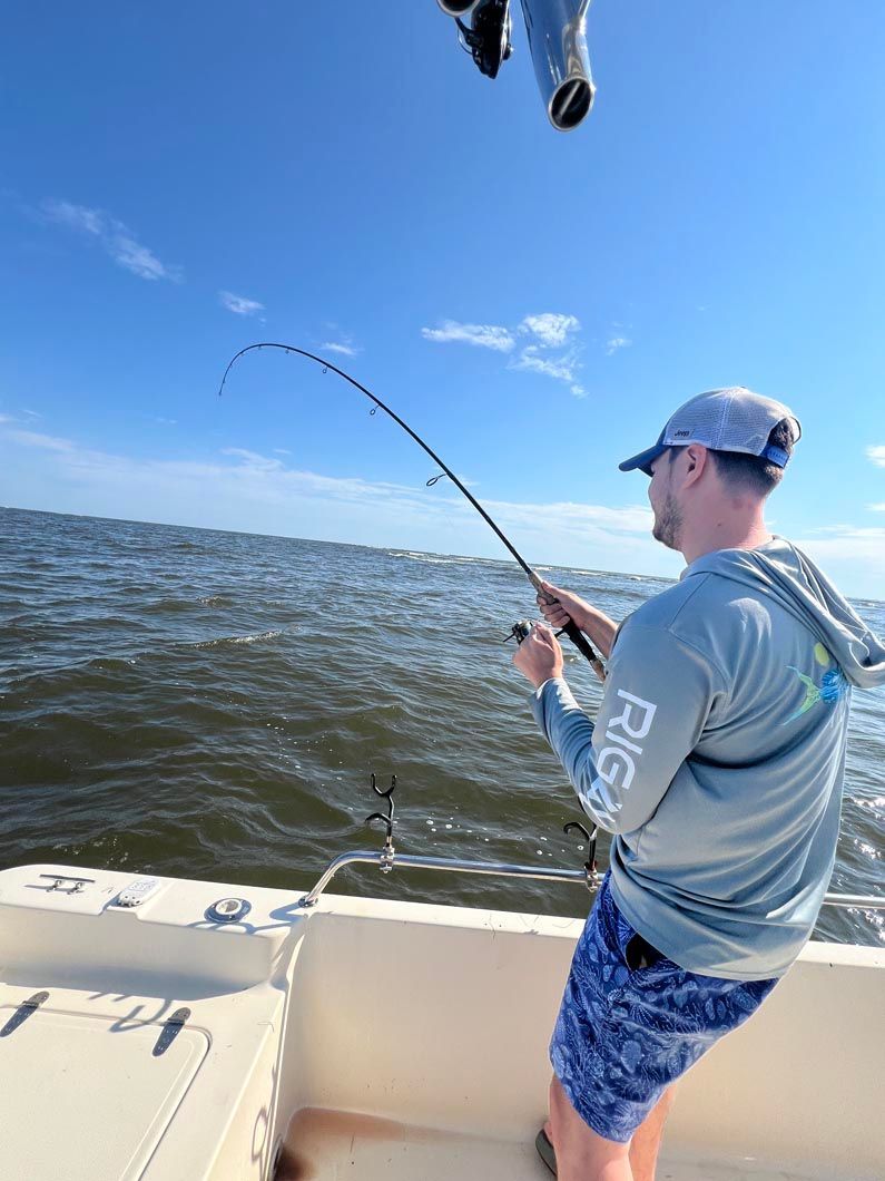 A man is fishing on a boat in the ocean.