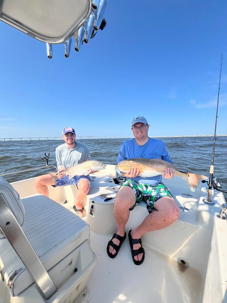 Two men are sitting on a boat holding a large fish.