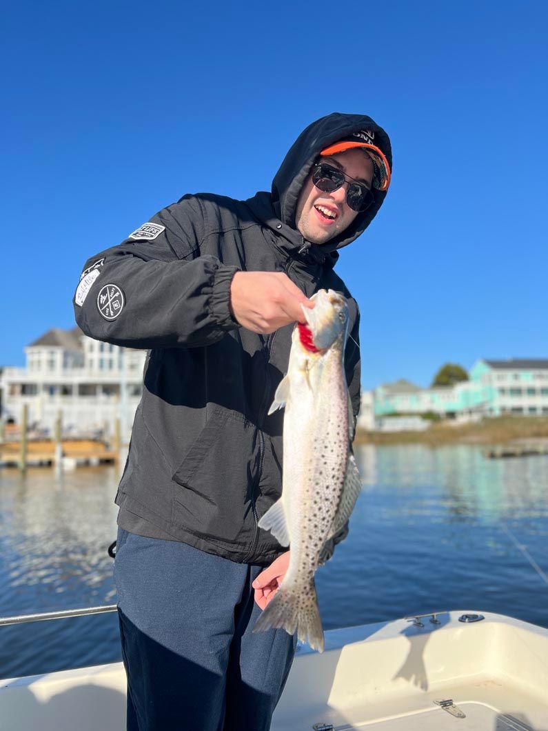 A man is holding a fish on a boat in the water.