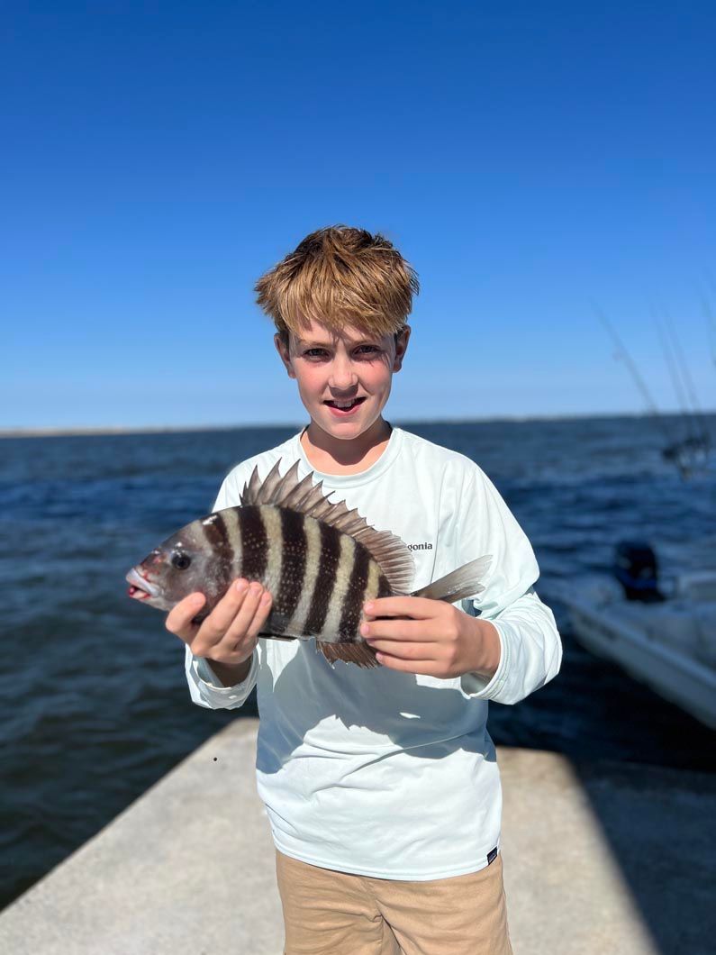 A young boy is holding a fish on a dock.