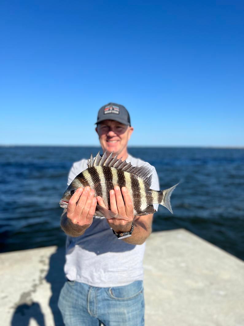 A man is holding a fish in his hands on a dock.