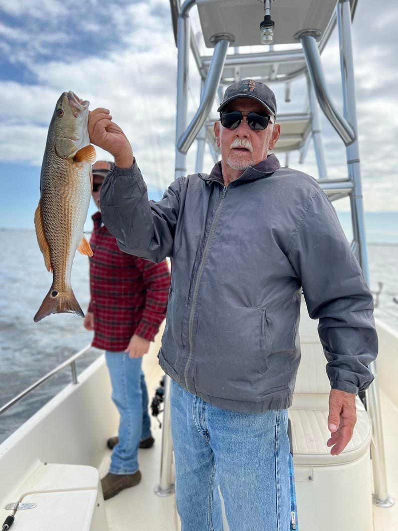 A man is holding a large fish on a boat.
