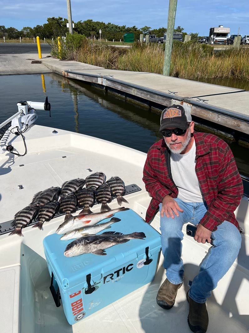 A man is sitting on a boat with a cooler full of fish.