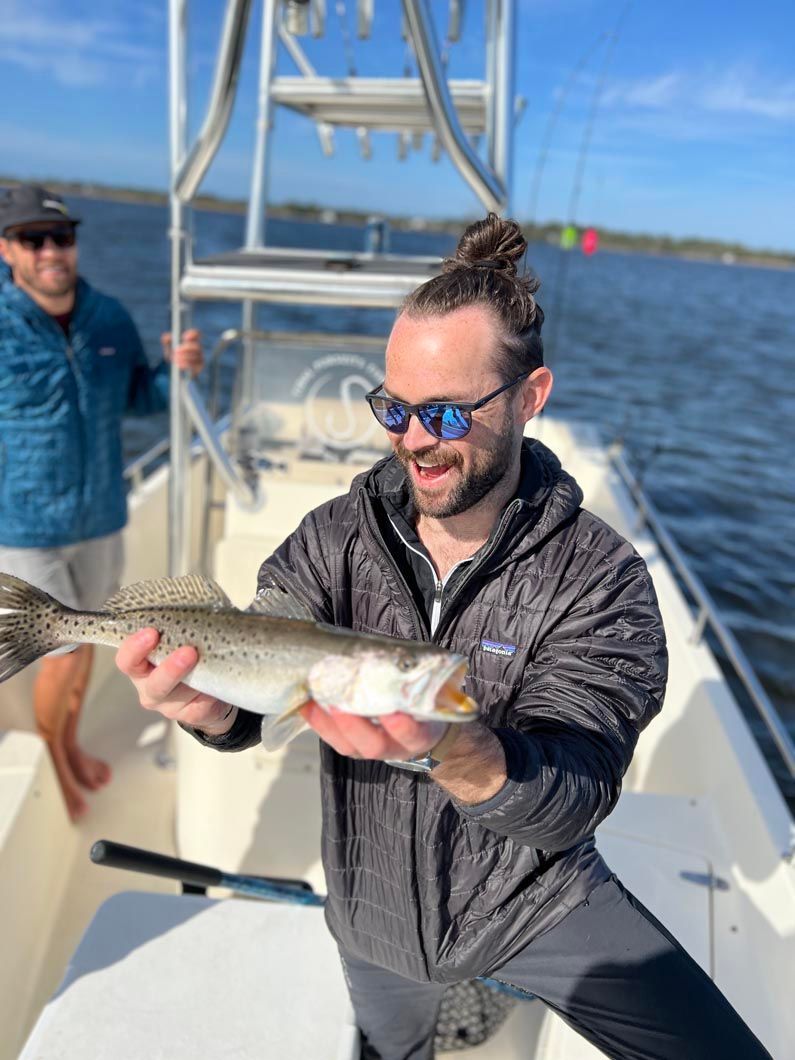 A man on a boat holding a fish in his hands