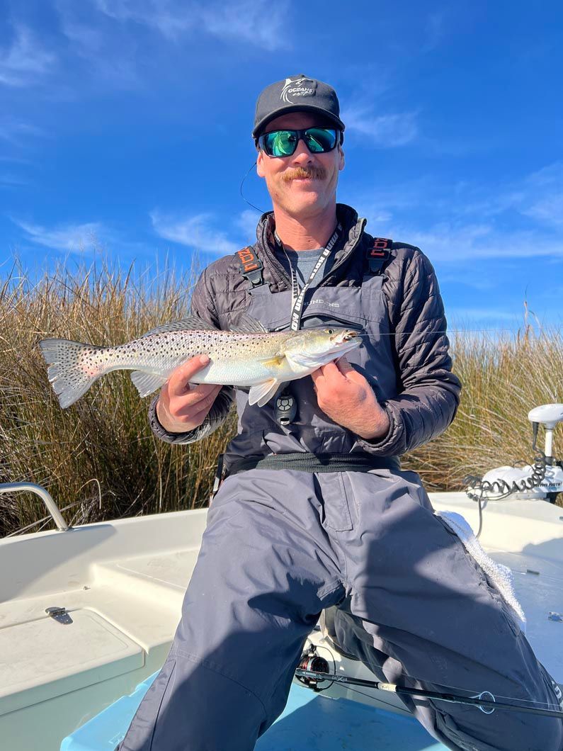 A man is sitting on a boat holding a fish.