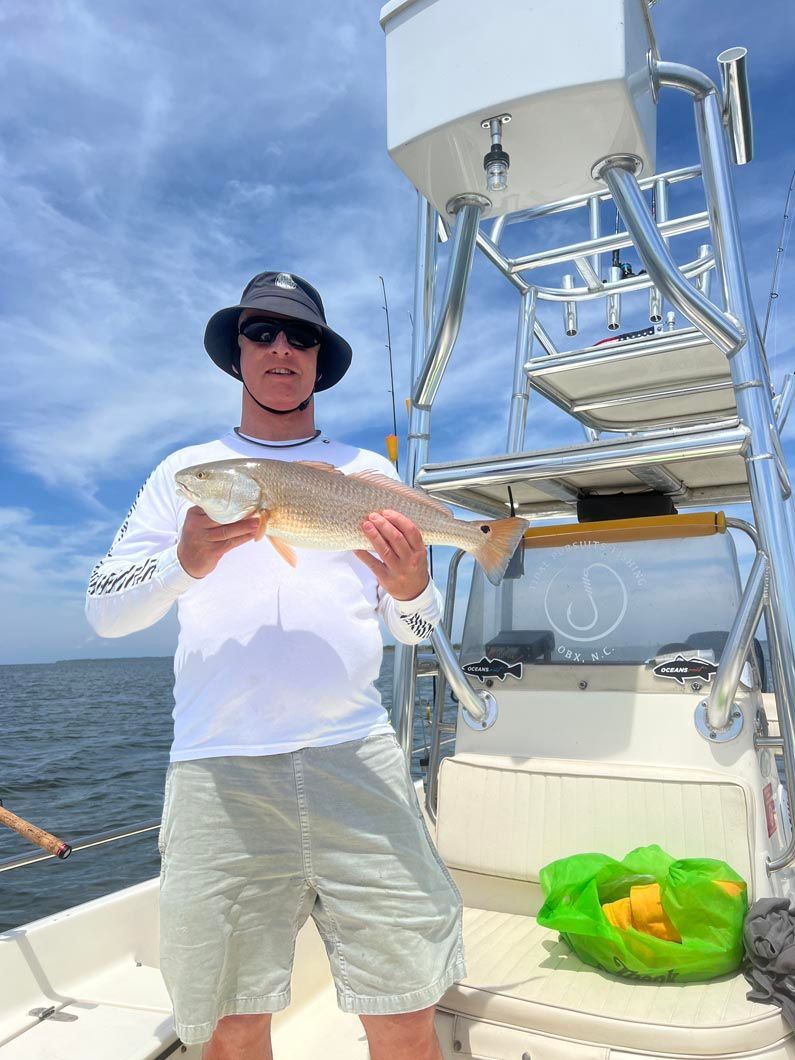 A man is standing on a boat holding a fish.
