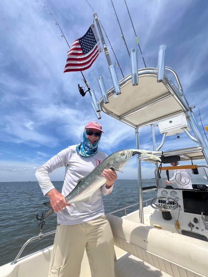 A man is standing on a boat holding a large fish.