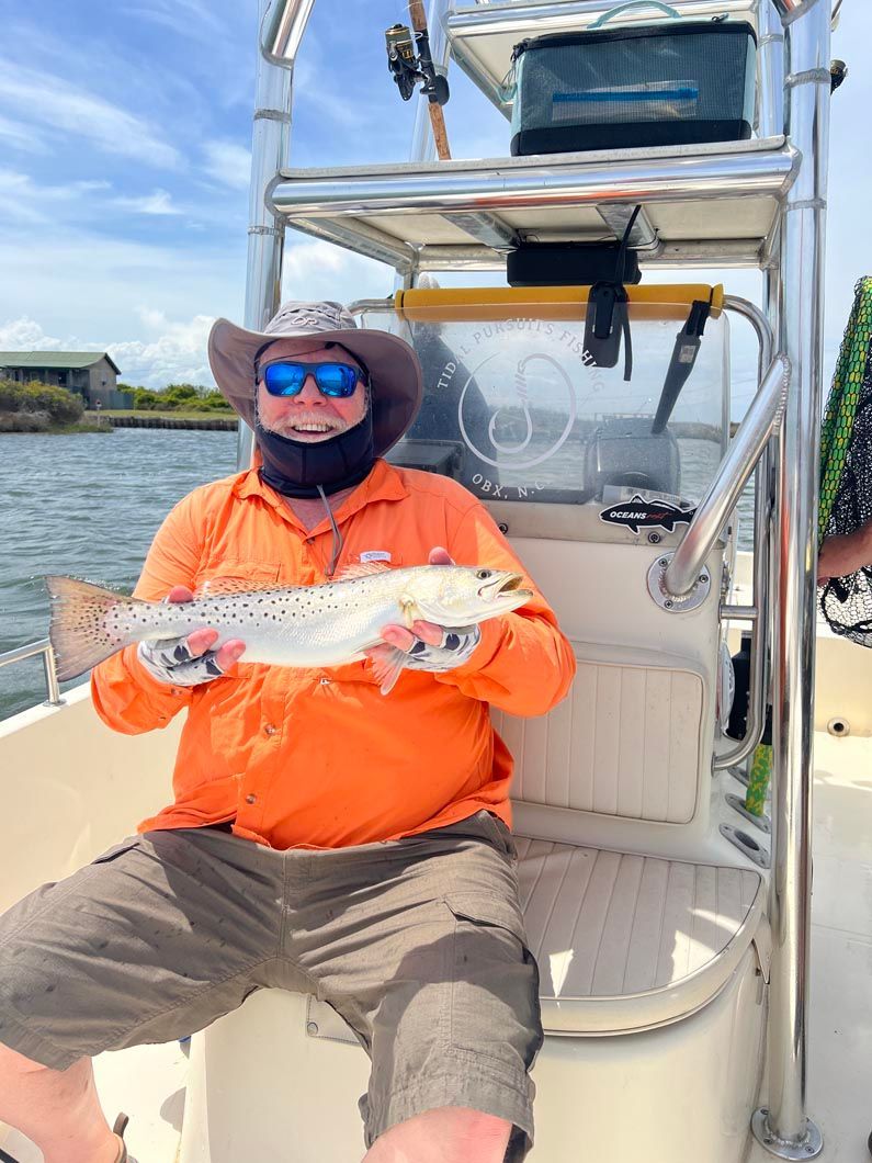 A man is sitting on a boat holding a fish.