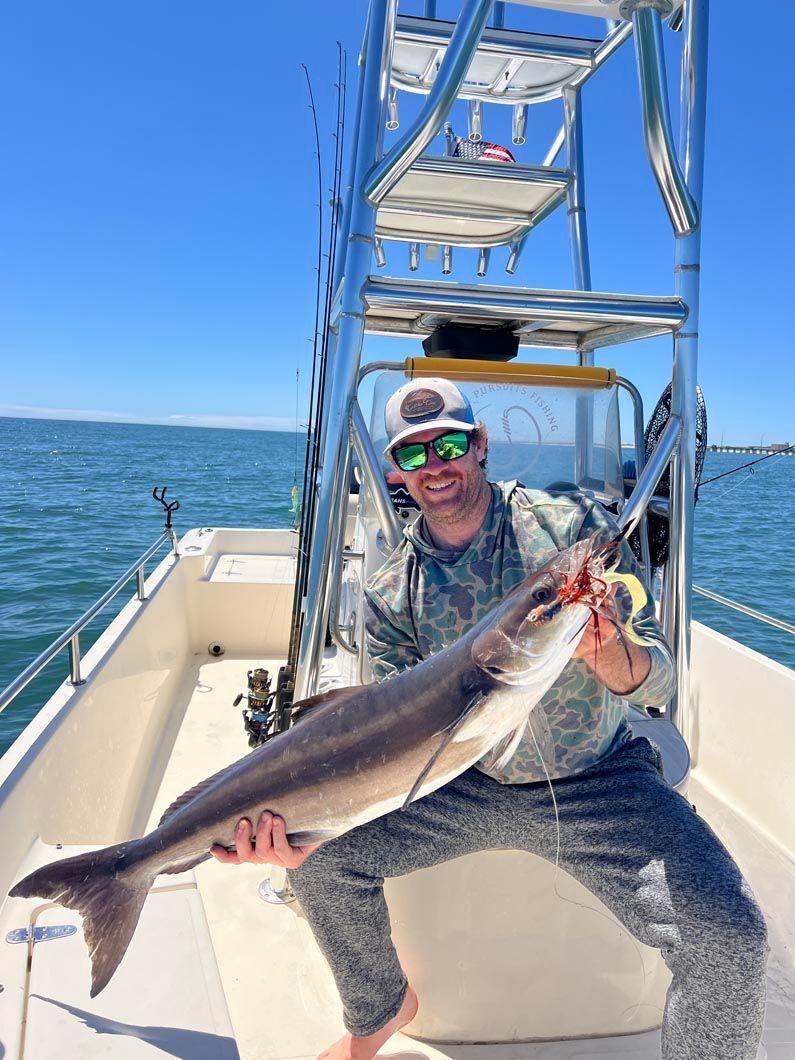 A man is holding a large fish on a boat.