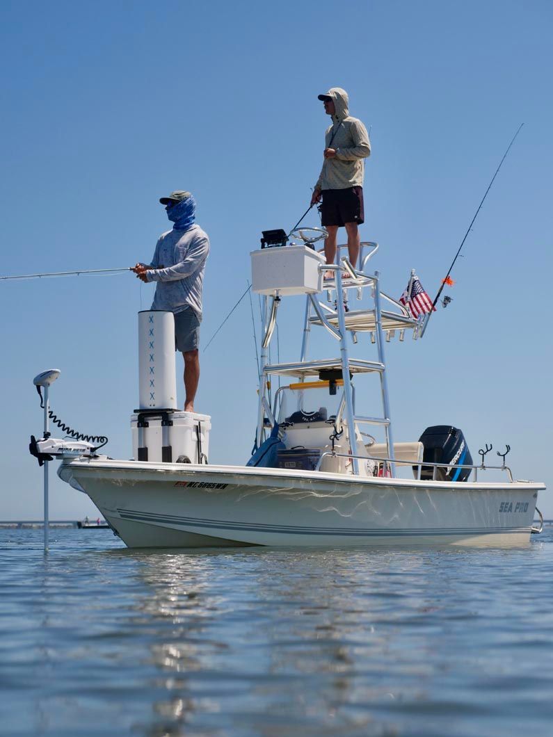 Two men are fishing on a boat in the ocean.
