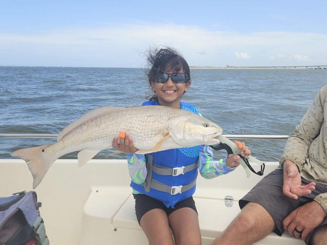 A little girl is sitting on a boat holding a large fish.