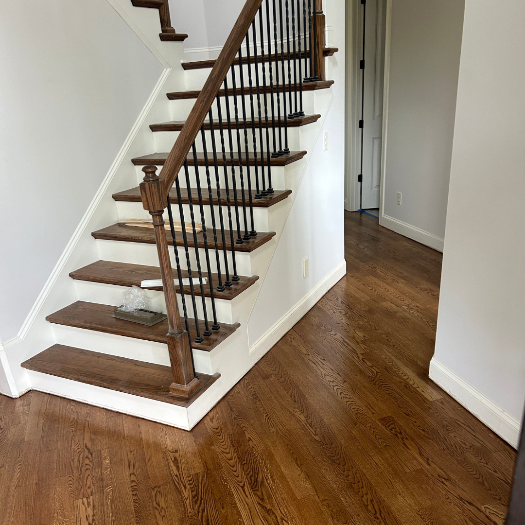 A wooden staircase with a metal railing in a room with hardwood floors.
