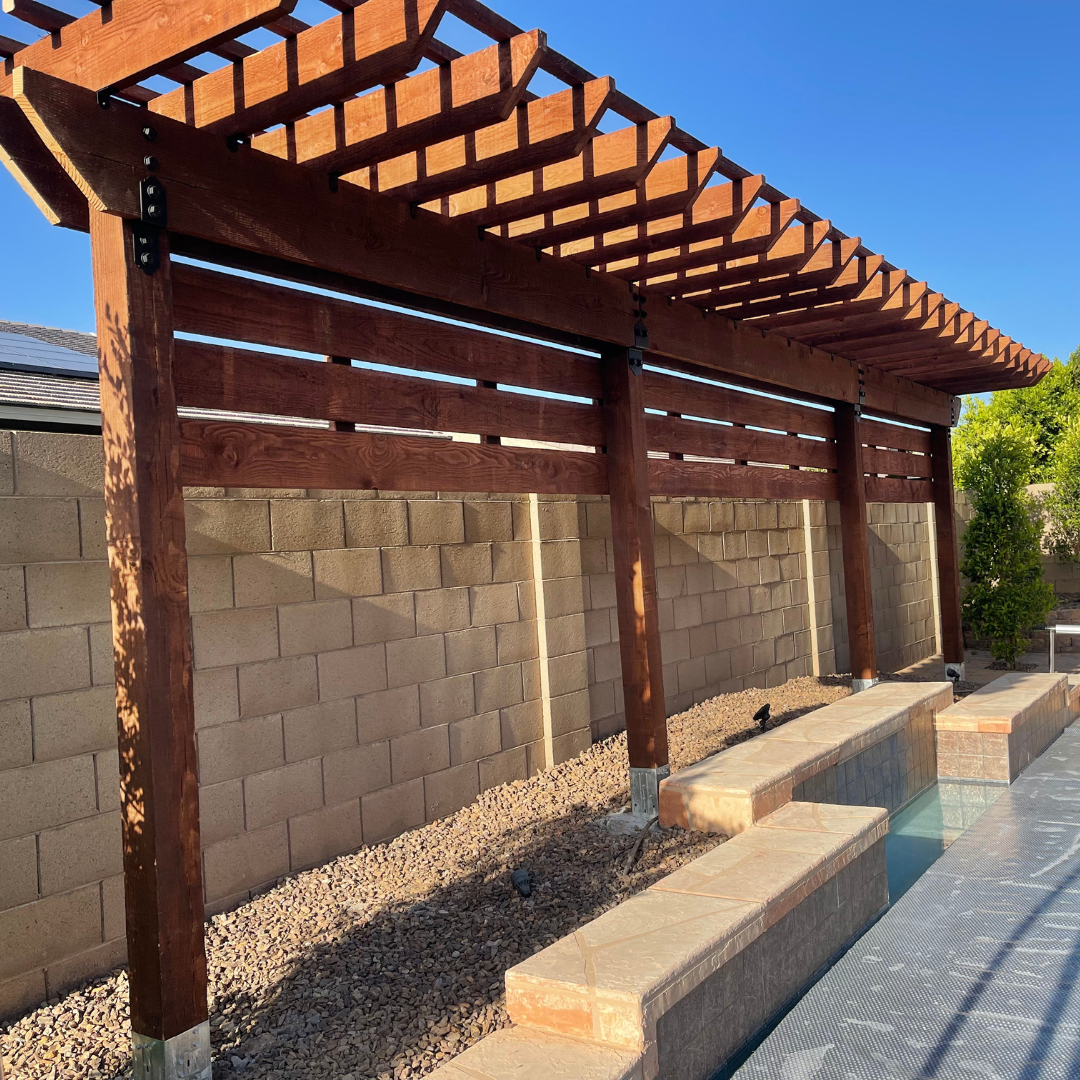 A wooden pergola over a brick wall next to a pool