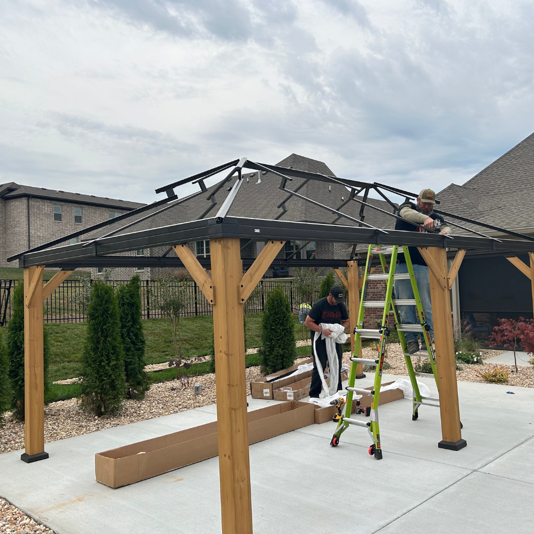 A man on a ladder is working on a gazebo