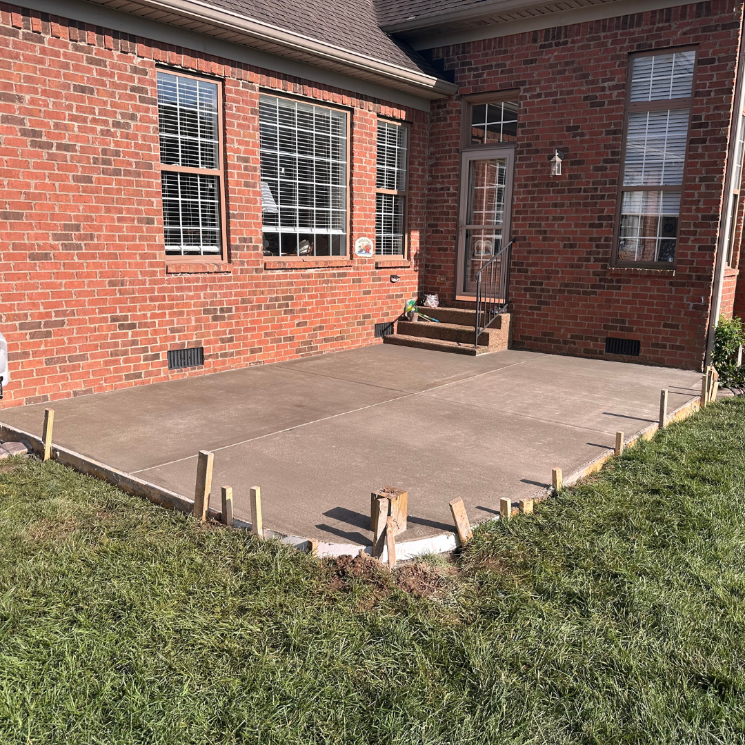 A brick house with a concrete patio in front of it.