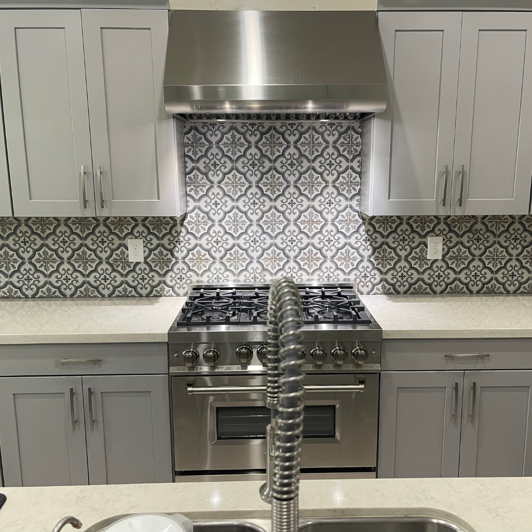 A kitchen with a sink , stove , oven and hood.