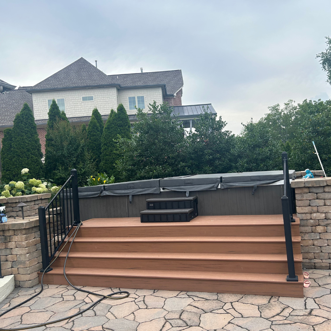 A hot tub with stairs leading up to it and a house in the background.