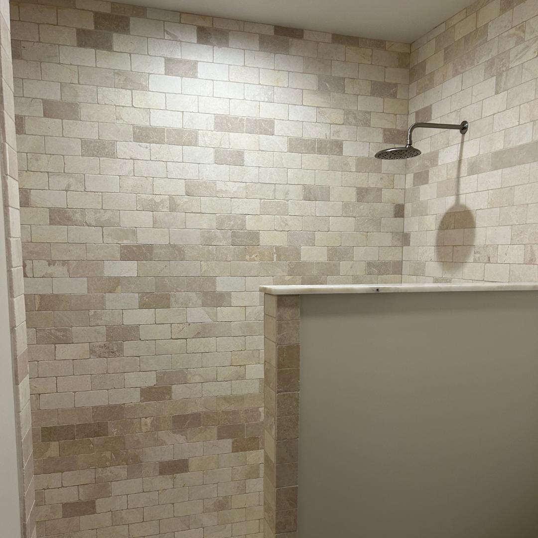 A shower with a brick wall and a shower head.