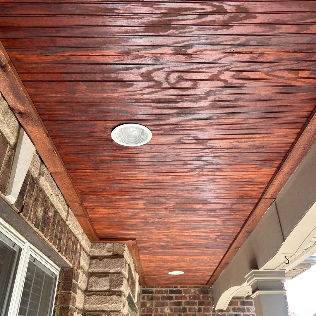 A porch with a wooden ceiling and a ceiling light.