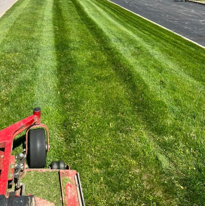 Lawn Mower on Green Grass — Northeast OH — Believeland Landscaping and Snow Removal