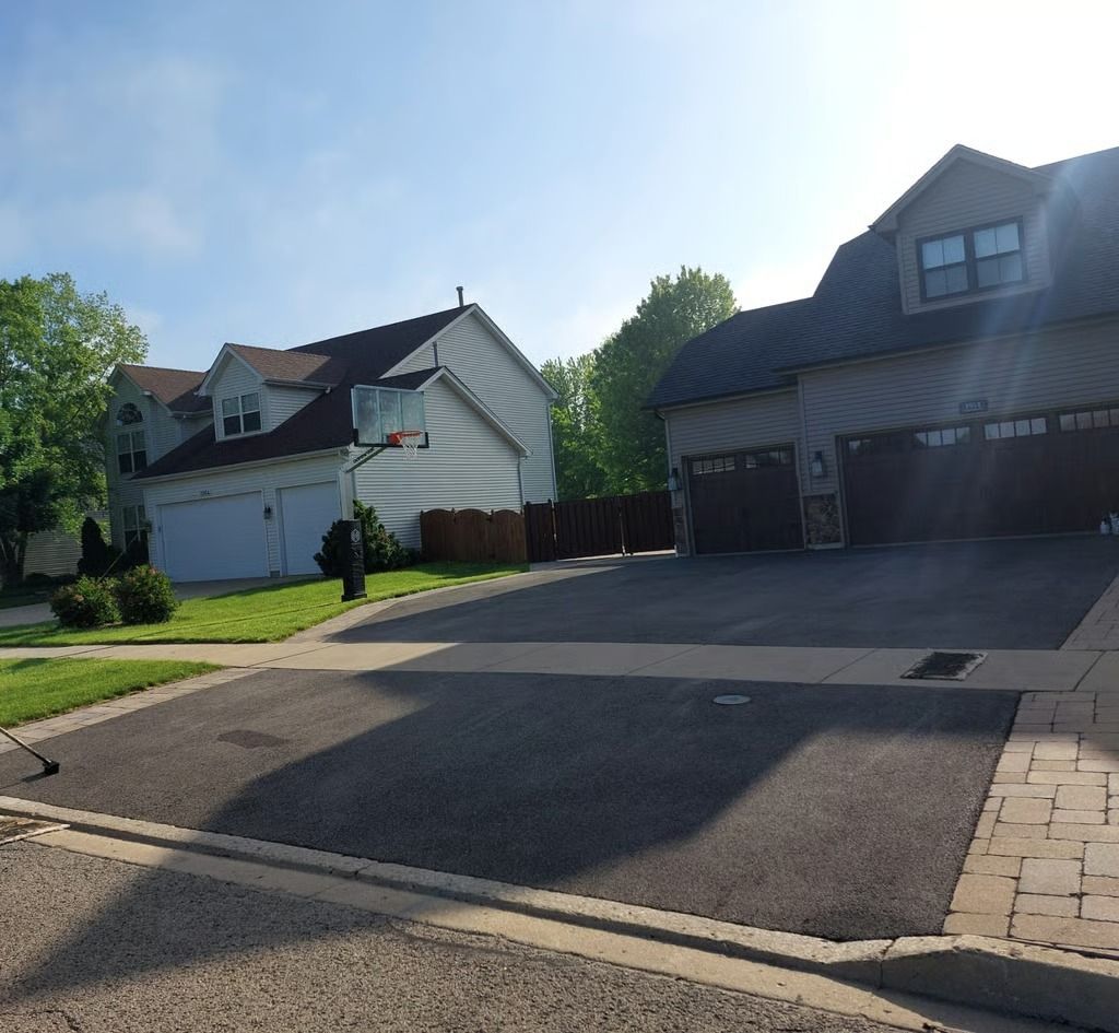 Suburban street with two houses, driveways, and trees in bright daylight