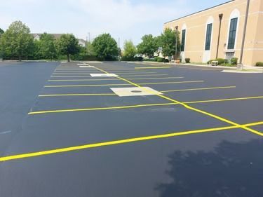 Empty parking lot with yellow lines beside a tan building on a sunny day