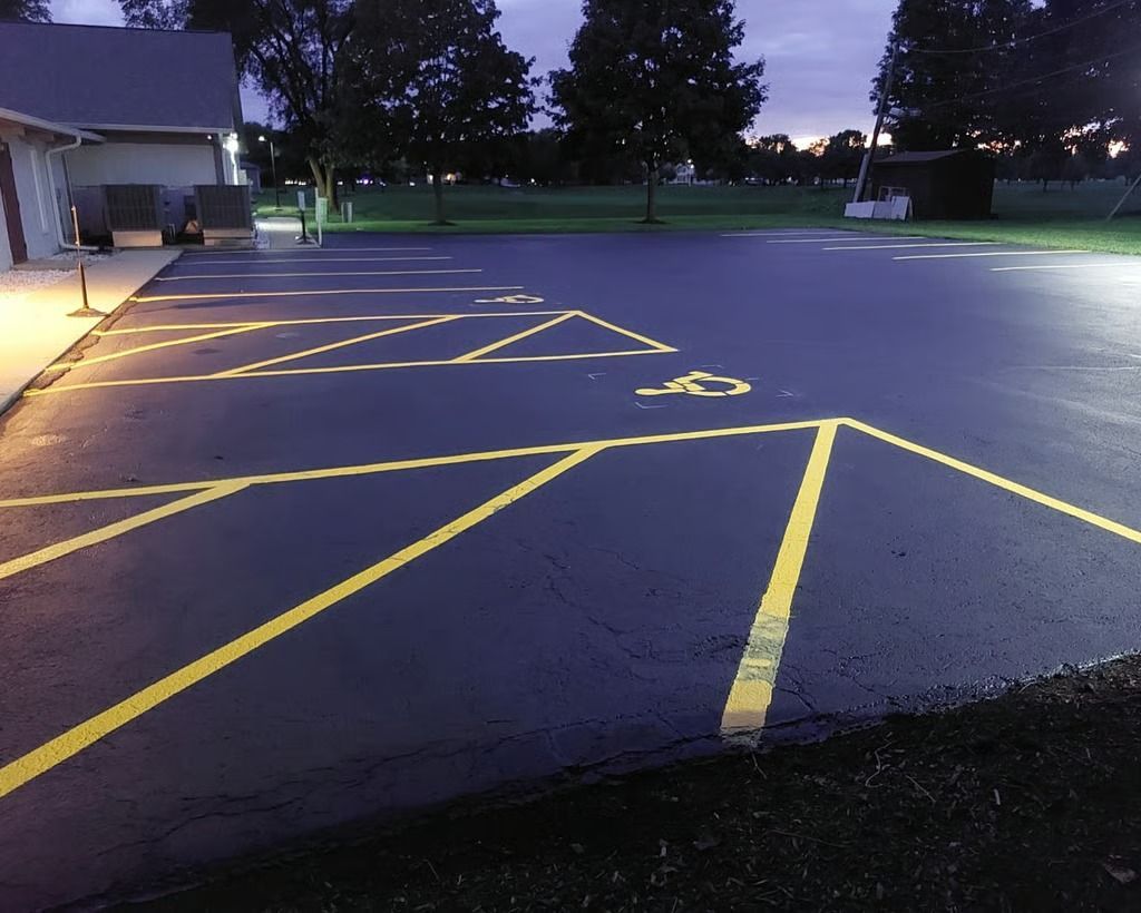 Empty parking lot at dusk with yellow painted pavement markings and a building on the left