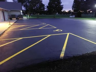 Empty parking lot with yellow handicap markings at dusk beside a building
