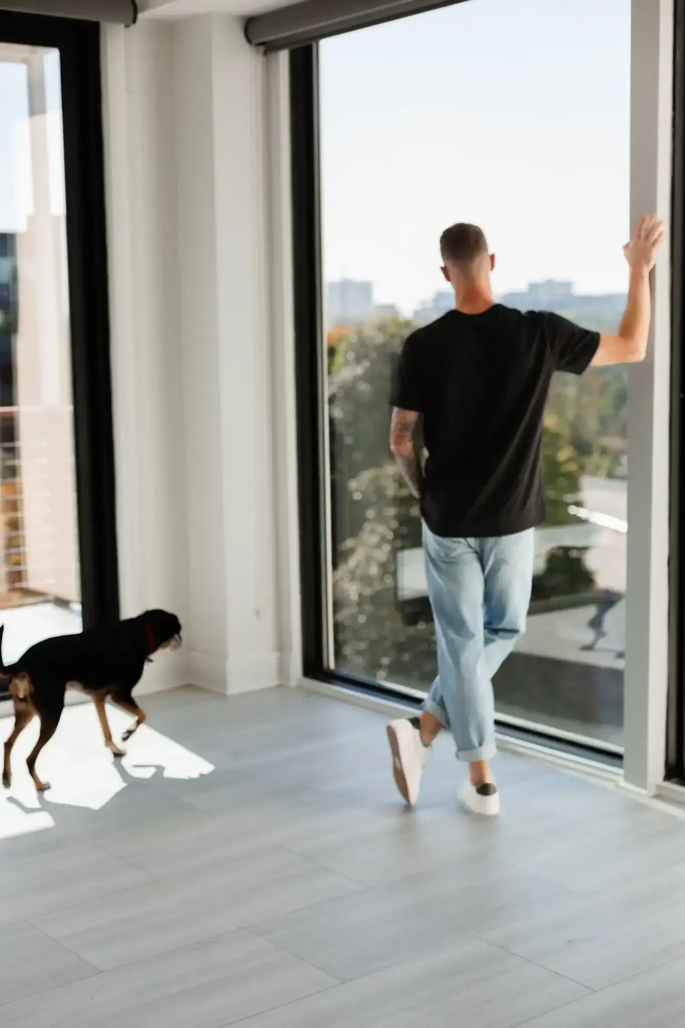 A man and a dog are looking out of a window.