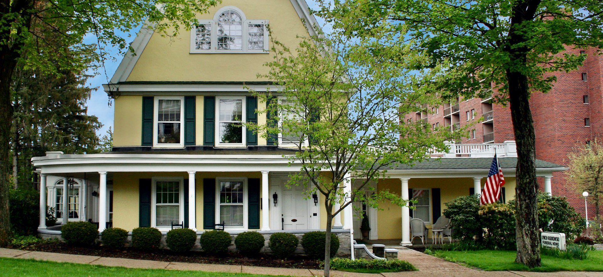 A large white house with a porch and trees in front of it