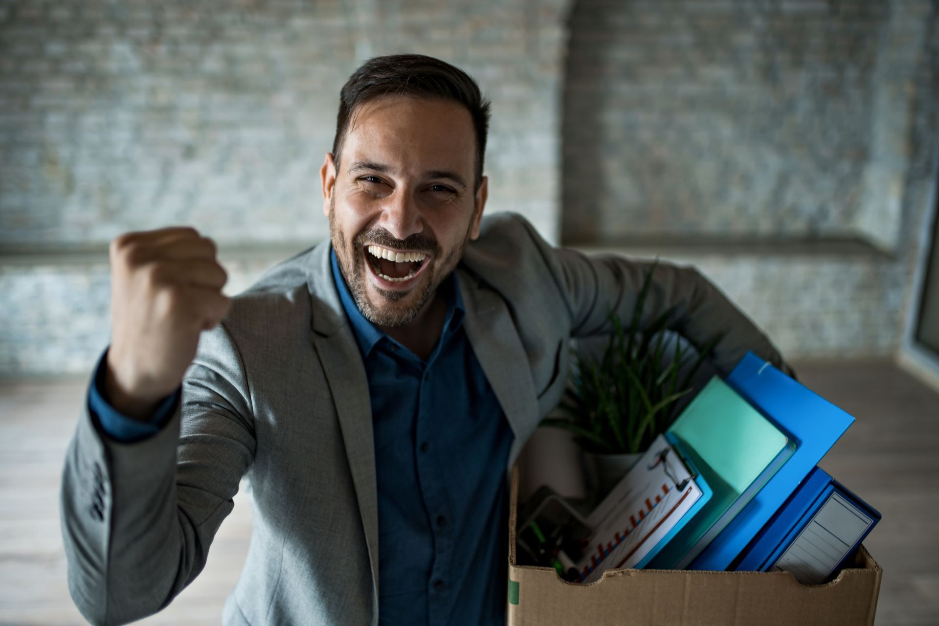 A man in a suit is holding a box full of his belongings.