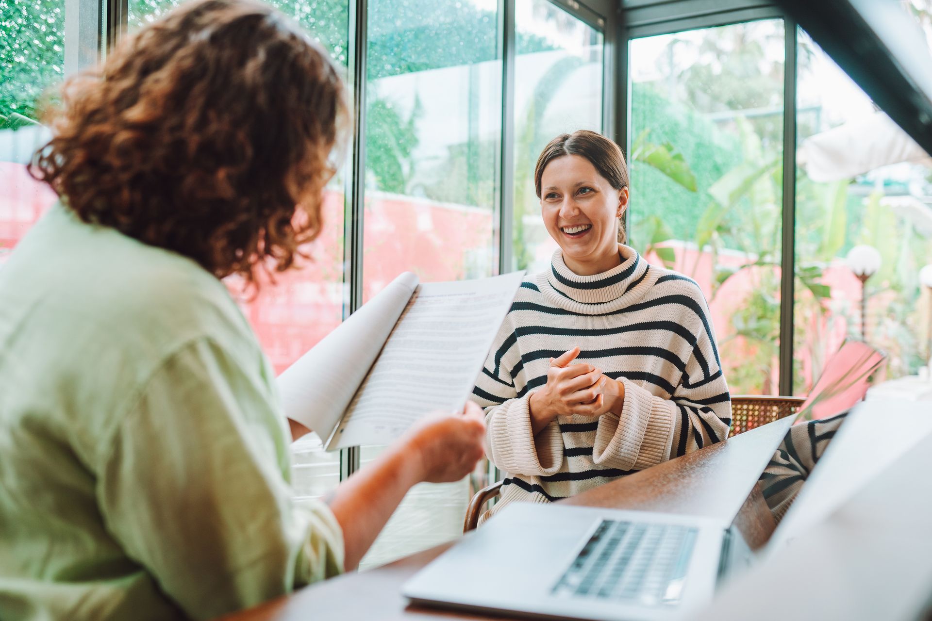 A woman is sitting at a table talking to another woman.
