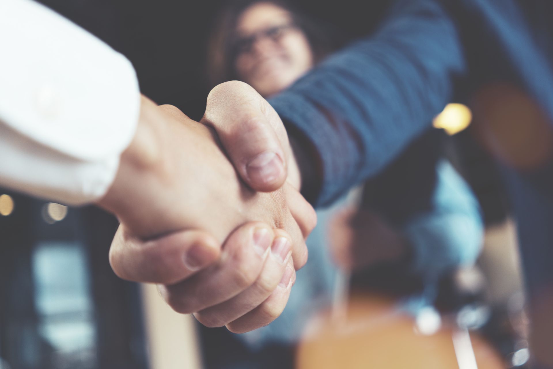 A man and a woman are shaking hands in an office.
