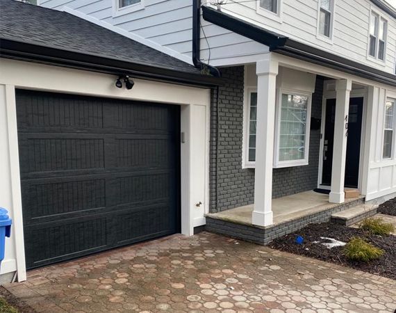 A white house with a black garage door and a porch – New Jersey - Local Garage Door
