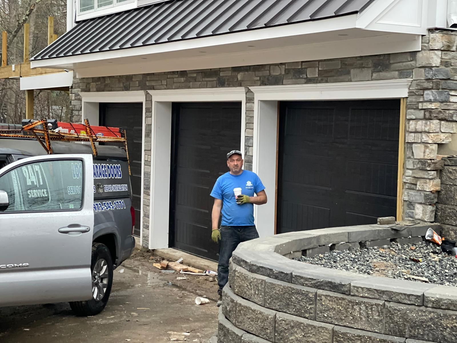 A man is standing in front of a garage door next to a truck – New Jersey - Local Garage Door