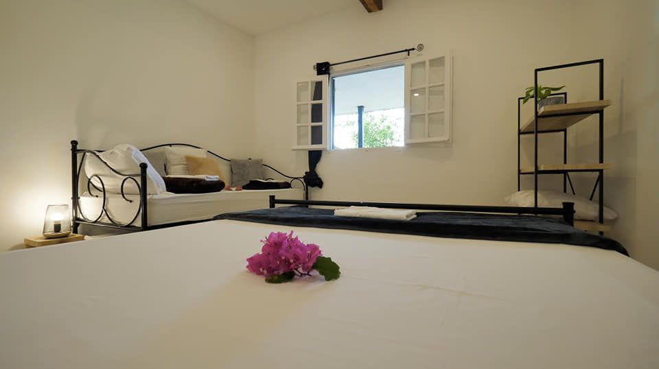 Une chambre avec un lit, un canapé et une fenêtre. le lit est orné d'une fleur.