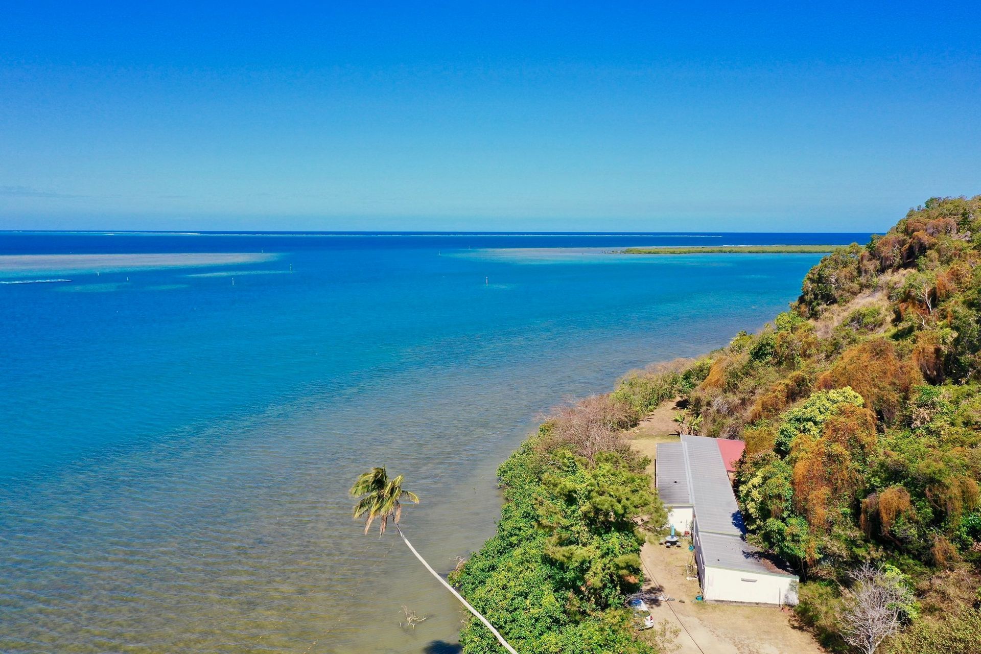 Une vue aérienne d’une maison sur une petite île au bord de l’océan.