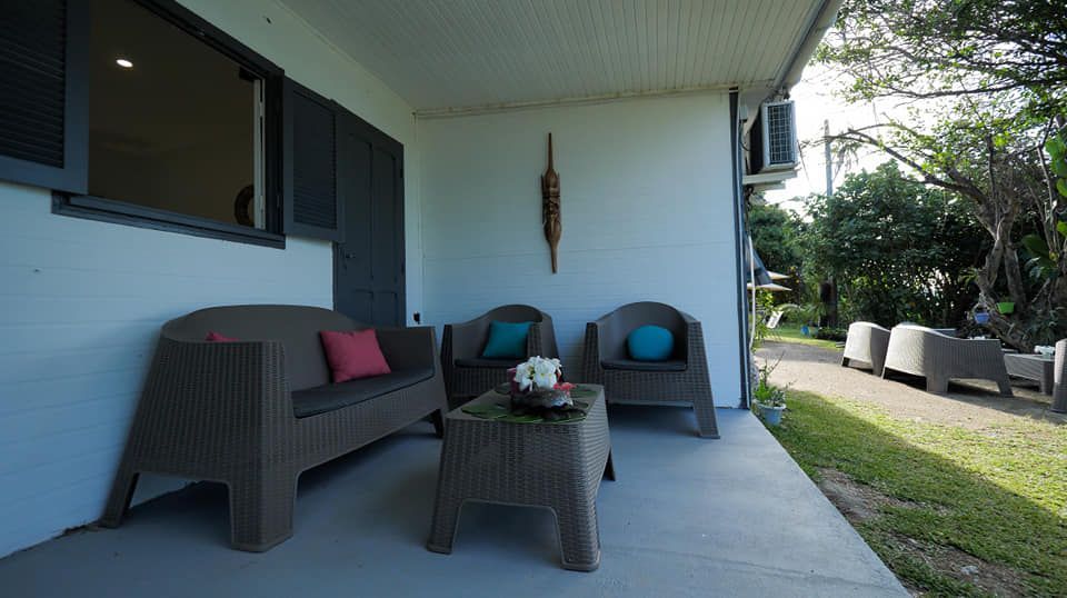 Un porche avec un canapé, des chaises et une table.