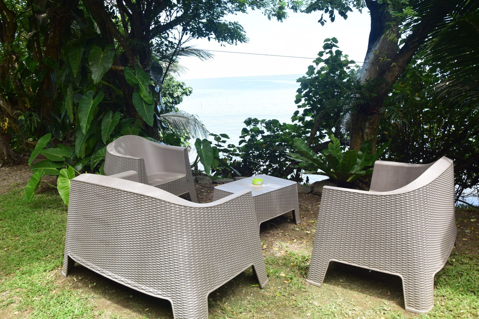 Deux chaises et une table sont posées dans l’herbe près de l’océan.