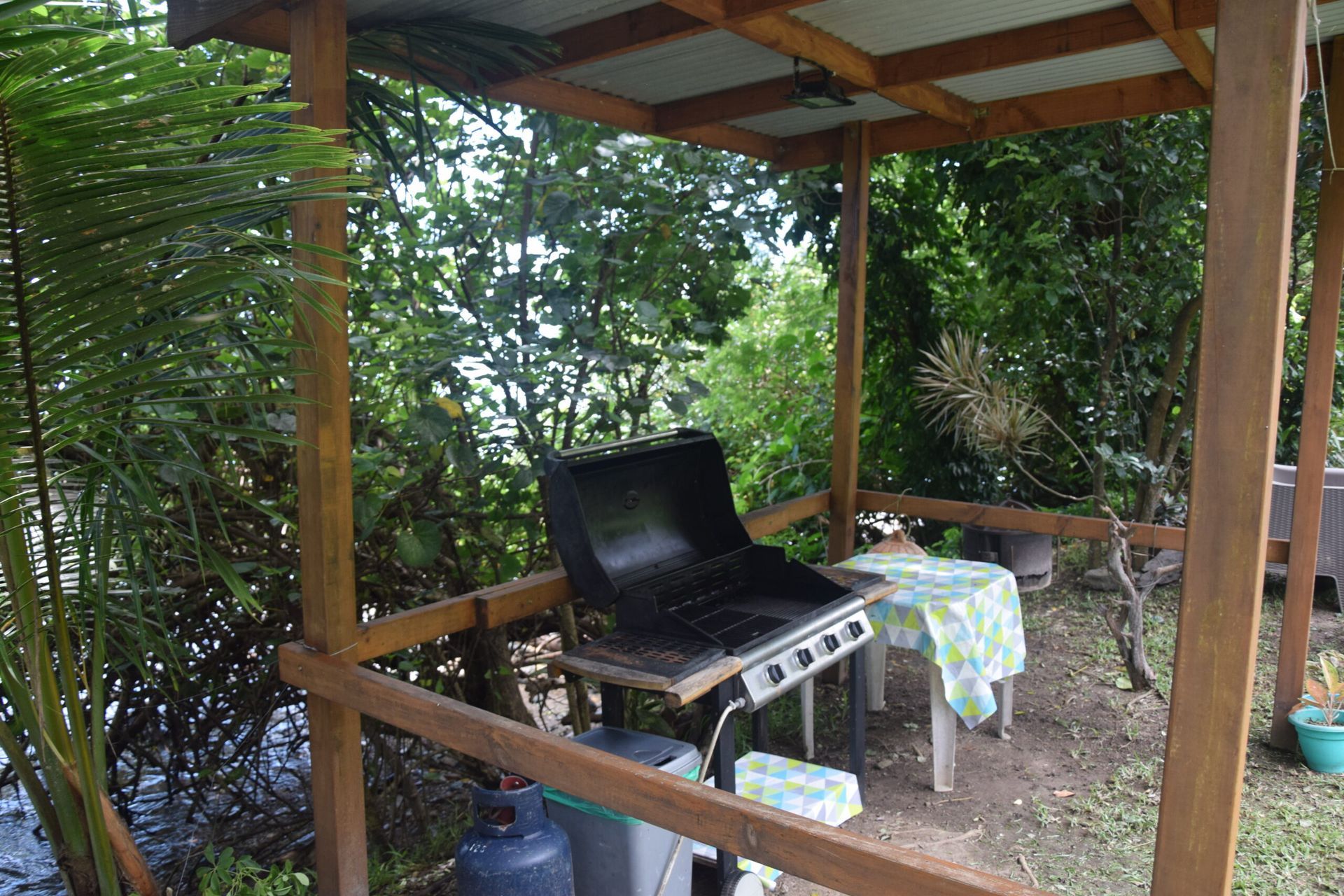 Un barbecue est installé sous un belvédère en bois.