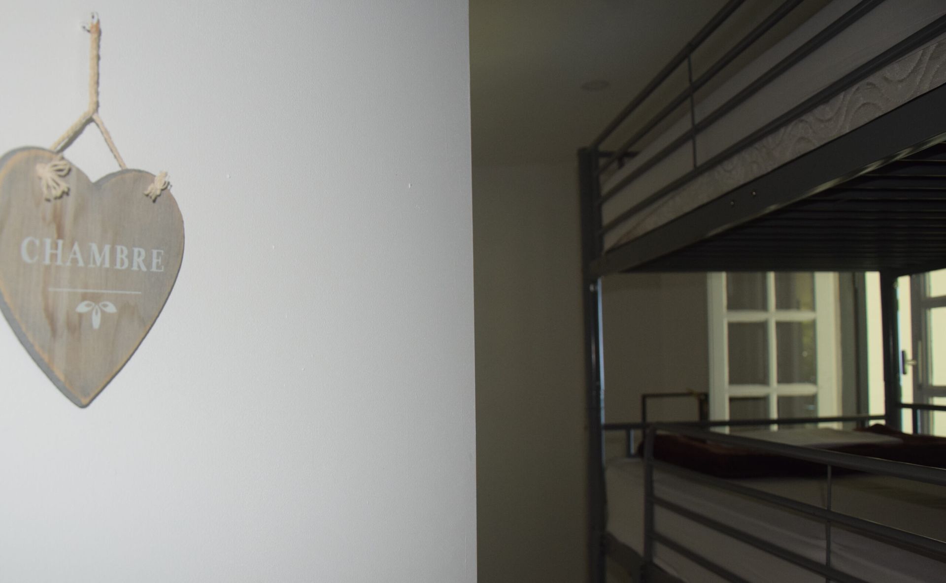 Une pancarte en forme de cœur est accrochée au mur à côté d’un lit superposé.