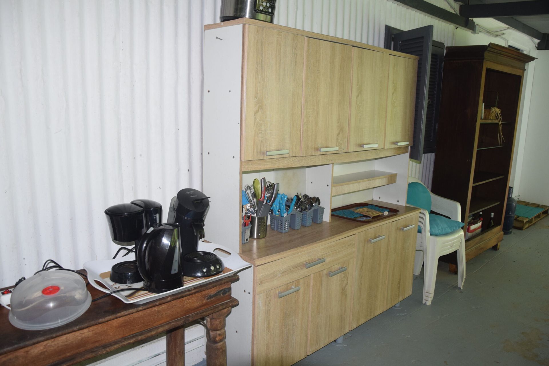 Une cuisine avec des armoires en bois et une table avec des cafetières dessus.