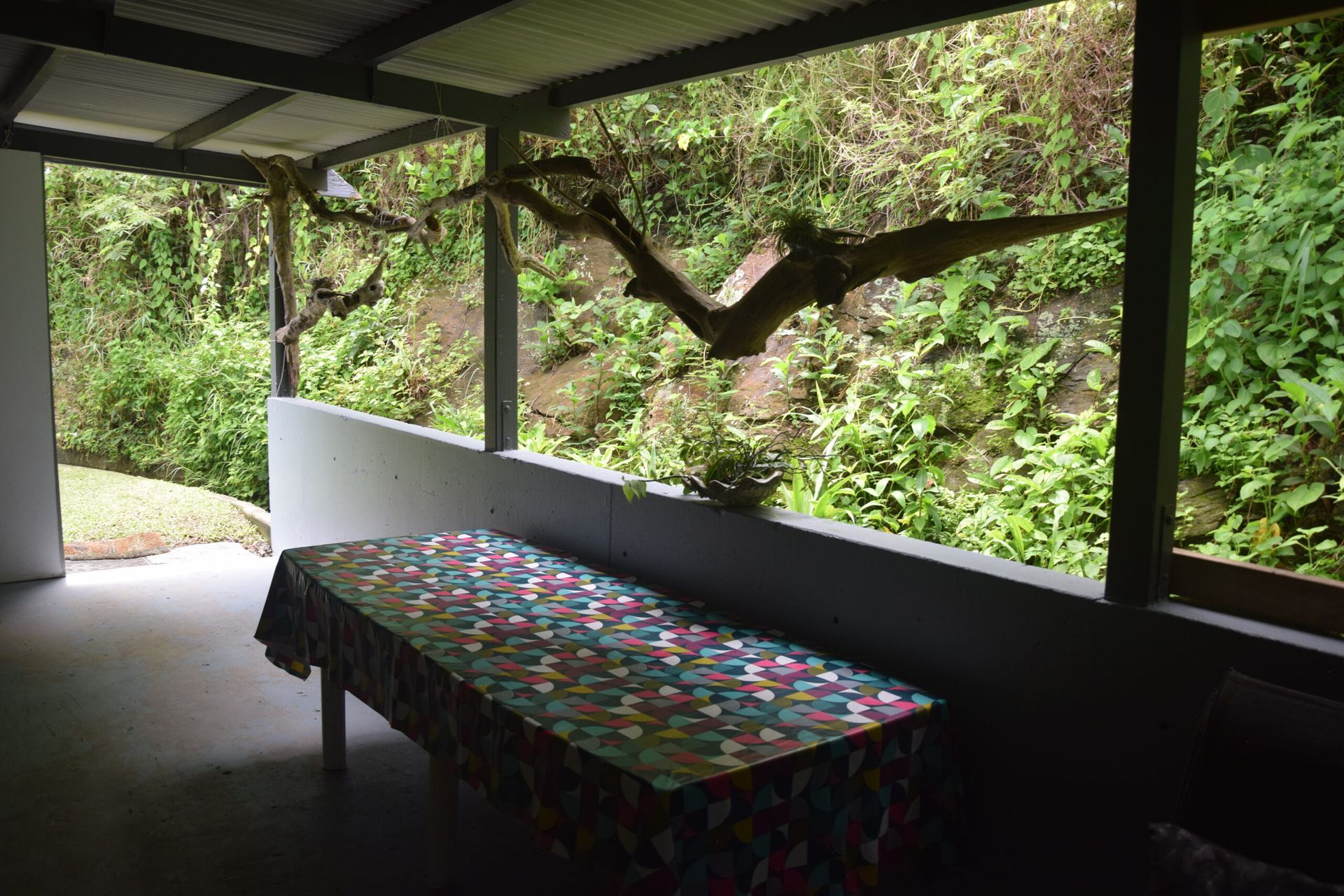 Une table avec une nappe colorée se trouve sous un porche couvert.