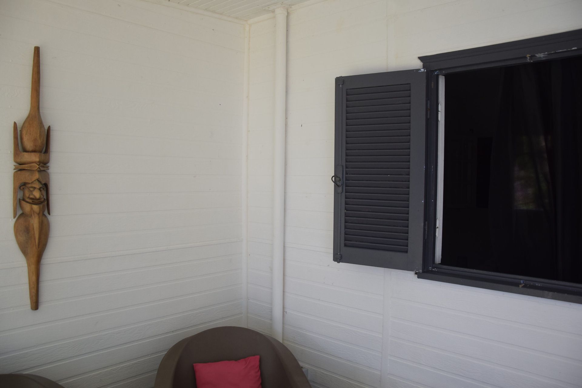 Une pièce avec deux chaises et une fenêtre avec volets ouverts