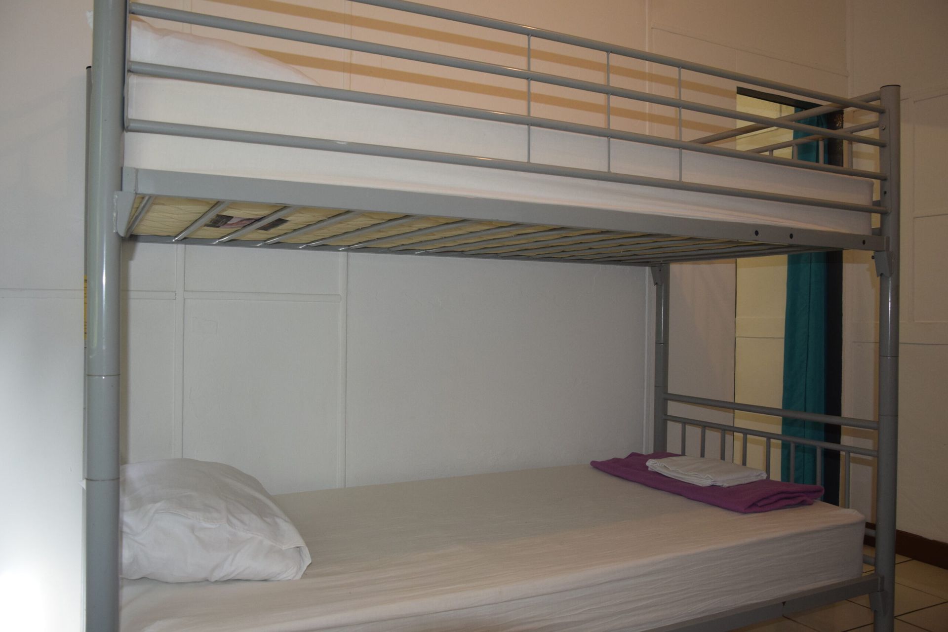 Un lit superposé avec un matelas blanc et une couette violette dans une chambre.